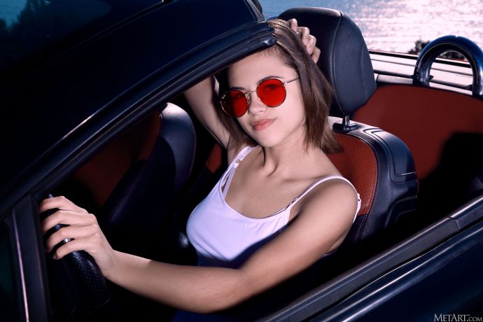 Голая девушка в кабриолете на фоне моря